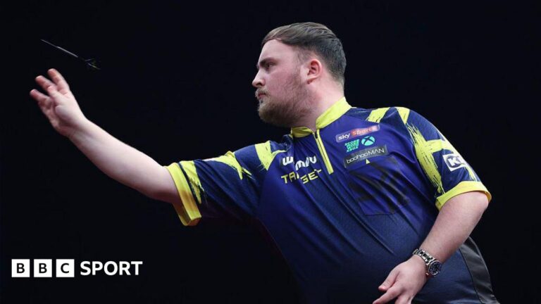 Luke Littler reaches World Masters round two after scare in Milton Keynes A side-on view of Luke Little as he throws a dart. He has dark hair, brushed forward, and a beard. His shirt is blue with yellow trim.