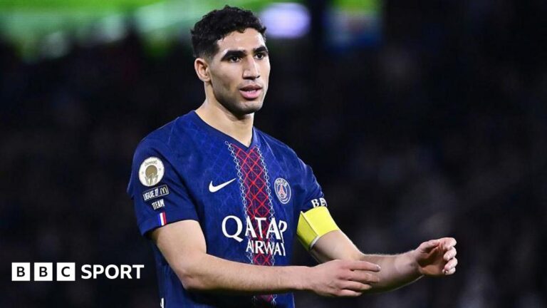 Achraf Hakimi: Paris St-Germain defender to face trial after rape allegation Achraf Hakimi, wearing a blue and red Paris St-Germain shirt, holds out his arms
