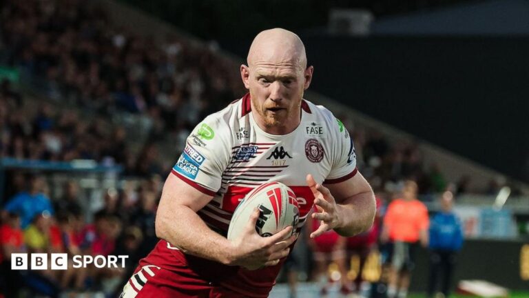 Liam Farrell scoring a try with the ball in his right hand for Wigan